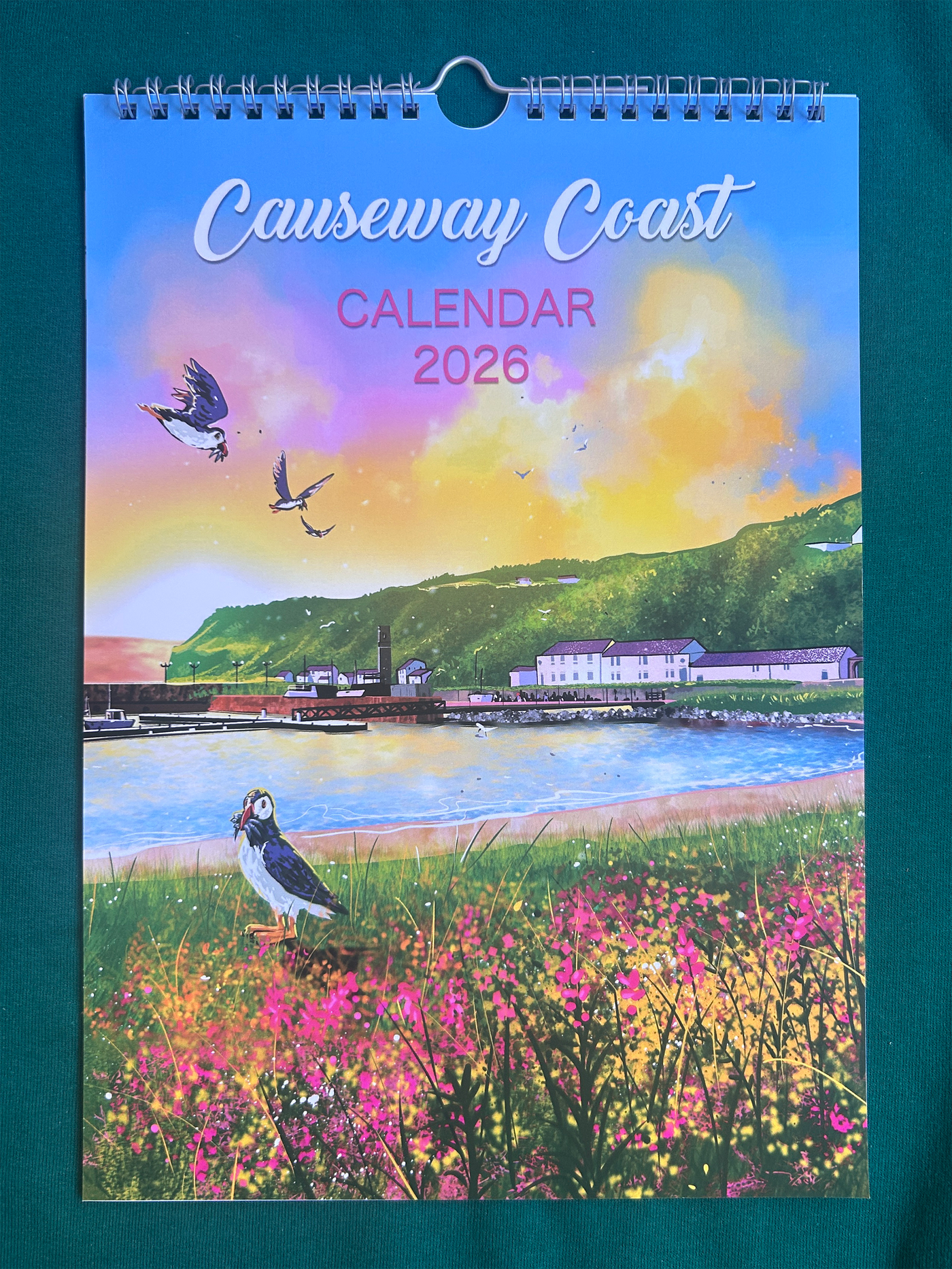 Causeway Coast calendar cover for 2026 with a scenic design of the Causeway Coast, featuring a coastal landscape with birds and flowers.